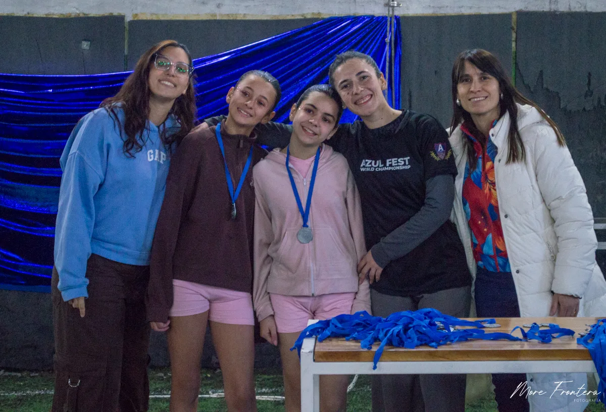 Premiación de Azul Fest Mar del Plata: Daiana Pedalino junto a alumnas con medallas, frente a las telas azules del escenario